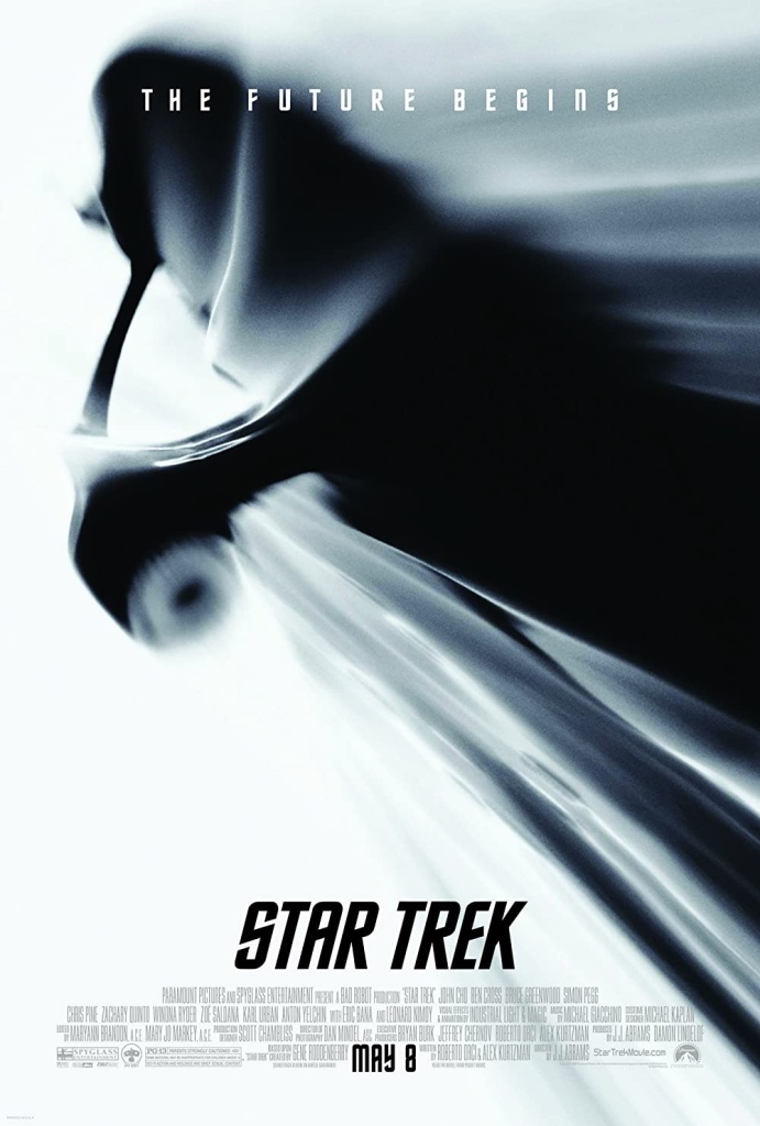 Star Trek (2009) poster. mainly white with a blurred silhouette of the Starship Enterprise appearing to take off at warp speed.  "The Future Begins" is in all caps at the top of the poster with the stylized Star Trek and film information are at the bottom.